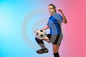 Female soccer, football player training in action isolated on gradient studio background in neon light