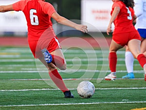 Female soccer player kicking the ball downfield