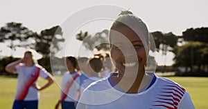 Female soccer player standing while teammates talk on soccer field. 4k