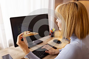 Female software developer eating pizza while working
