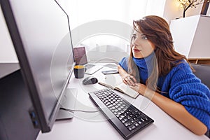 Female software developer taking notes while working remotely from home