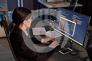 Female software developer writing code while using computer at workplace