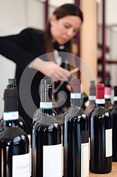 Female sommelier uncorking a bottle of red dolcetto wine in piedmont, italy