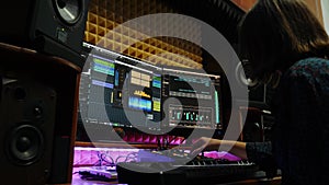 Female songwriter creating song with monitors and equalizer mixing gear on screen at professional recording studio. Woman playing