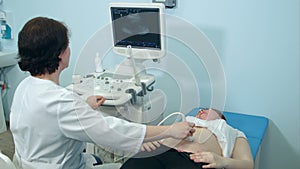 Female sonographer holding an ultrasound transducer to diagnose the condition of a pregnant woman