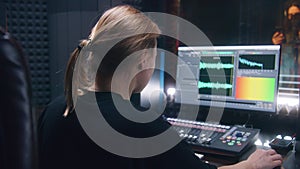 Female sound engineer uses control mixing surface and computer