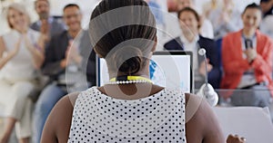 Female speaker and applauding audience at a business conference