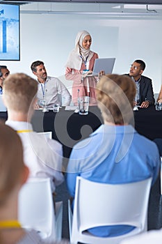 Female speaker with laptop speaks in business seminar