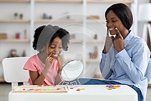 Female speech pathologist exercising with little girl with language difficulties