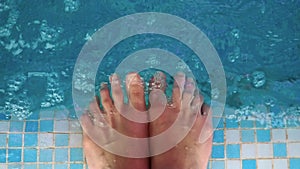 Female Splashing Feet In Fresh Clear Swimming Pool