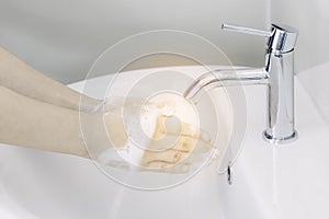 Female splice or clasp hands under tap water at lavatory and cleansing with soap foam. Concept good hygiene and coronavirus