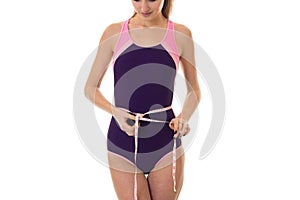 Female sport slim body in simsuit measure waist with tape isolated on white background