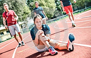 Female sportler getting injured at athletic workout training - Male coach taking care on sport pupil after physical accident