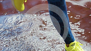 Female sports woman jogging outdoors, stepping into puddle. Single runner running in rain, making splash. Slow motion