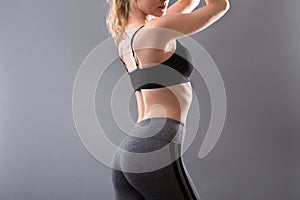 Female sportswear clothes on perfect body. Sport bra and grey leggins pants photo