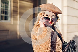 Female spring fashion. Stylish woman wearing clothes, accessories beret, sunglasses, coat with purse. Outdoor portrait
