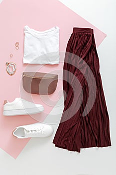 Female spring look summer outfit burgundy skirt white shoes sneakers white basic tshirt waist bag. Folded fly clothes