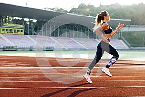 Female sprinter race on outdoor track arena. Female marathon runner on professional sports arena. Fitness woman racing