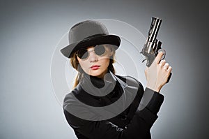 Female spy with weapon against gray