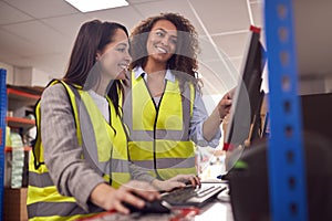 Female Staff In Busy Modern Warehouse Working On Computer Terminals