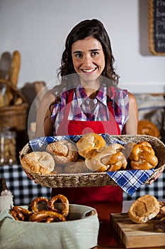 Female staff holding basket of sweet foods in bakery section