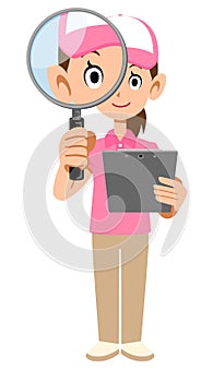 A female staff member wearing a short-sleeved polo shirt and hat looking into a magnifying glass while holding a document in her