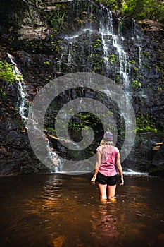Female standing at base of a mountain waterfall