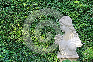 Female statue made from mortar in the summer garden with copy space. Decorative gardens