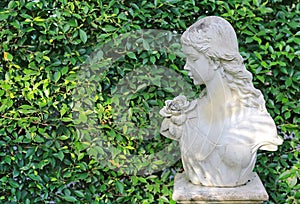 Female statue made from mortar in the summer garden with copy space. Decorative gardens