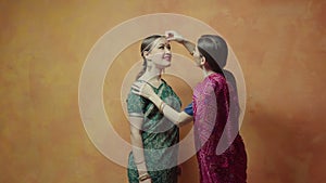 Female sticking red bindi point to beloved friend