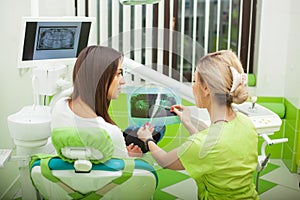 Female stomatologist in protective gloves examining patient`s teeth. Dentist caries treatment at dental clinic office