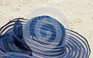 female straw hat blue hat lies on the sand casts a shadow on a bright day beach holidays