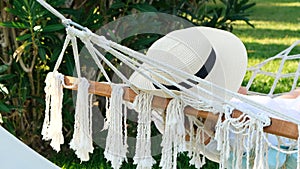 female in a straw hat is resting in a hammock around the palm trees and enjoying the tranquility and relaxation