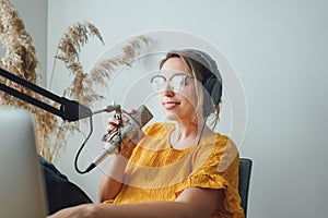 Female streaming his audio podcast using microphone and laptop at his small broadcast studio