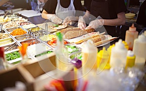 Female street vendor hands making sandwich outdoors. cuisine snacks, cooking fast food for commercial kitchen.