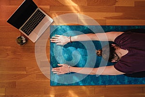 Female stretching over a mat during online yoga class