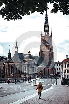 Female strolls along a cobblestone street in front of the Riddarholmen Church in Stockholm, Sweden