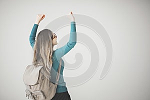 Female student arms raised with backpack on grey background