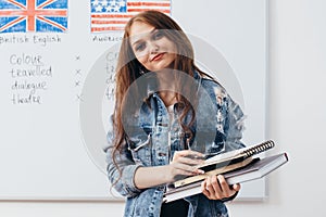 Female student with books in classroom English language school.