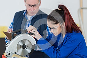 female student in carpentry class using circular saw