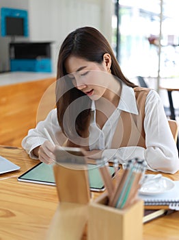 Female student concentrating on her project with stationery and tablet on table