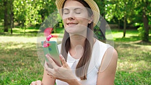 Female student cooling down with pink portable ventilator attached to mobile phone during heat