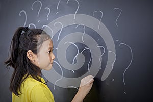 Female student drawing question marks in classroom