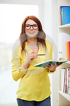 Female student in eyeglasses with book and pencil