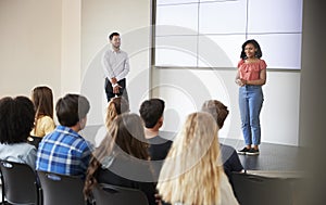 Female Student Giving Presentation To High School Class In Front Of Screen