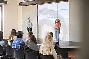 Female Student Giving Presentation To High School Class In Front Of Screen