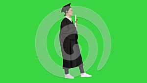 Female student in graduation robe holding diploma and waiving it around on a Green Screen, Chroma Key.