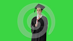 Female student in graduation robe holding diploma and waiving it around on a Green Screen, Chroma Key.