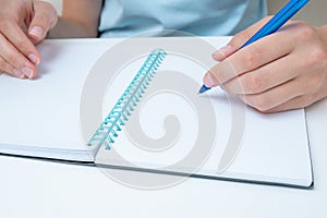 Female student hand holding a pen writing in a notebook, large poan. Business woman makes a note in a notebook