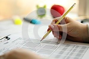 Female student hands testing in exercise and taking fill in exam paper sheet with pencil at school test